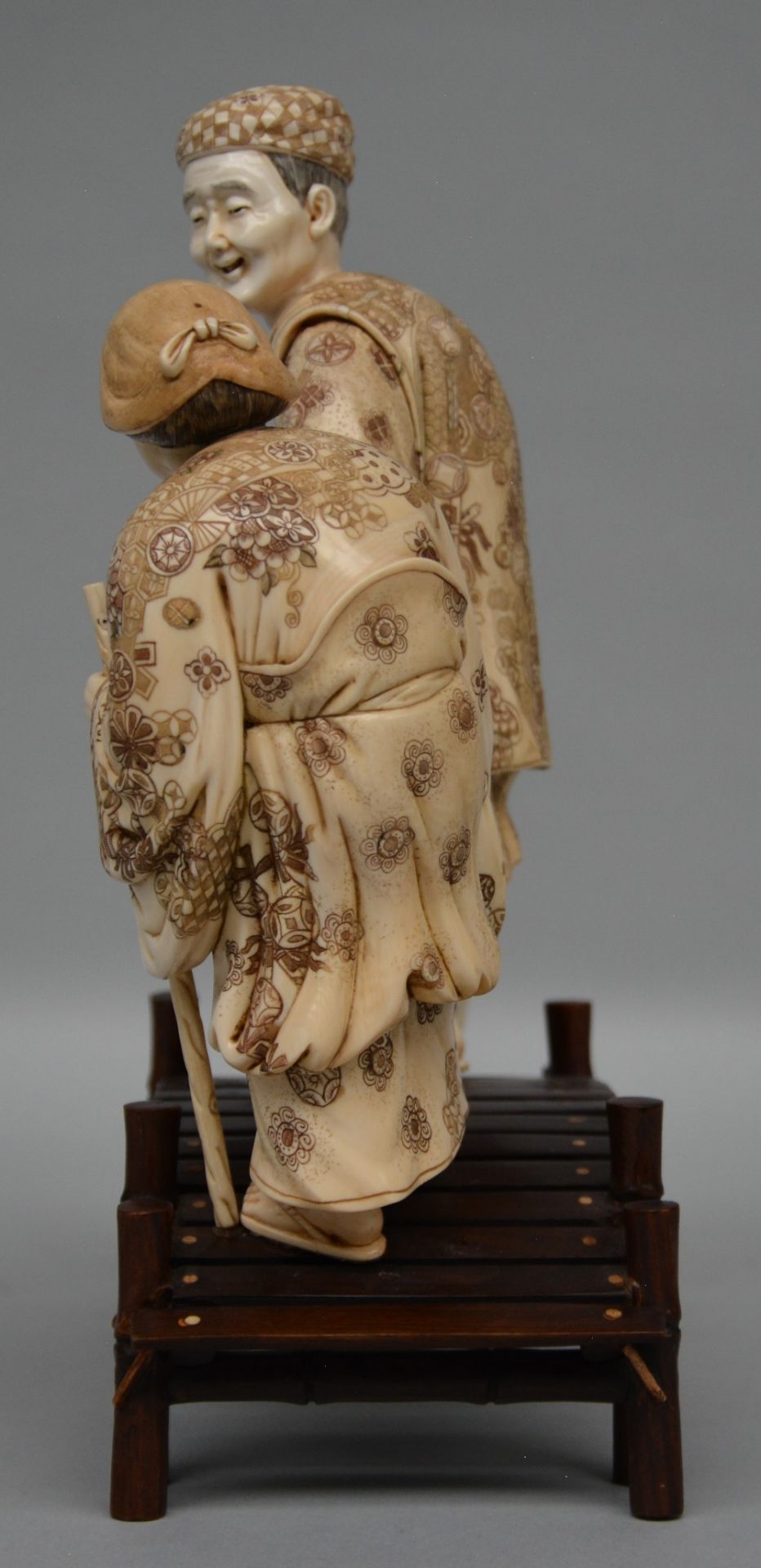 A charming Japanese ivory okimono depicting two figures and a dog on a bridge, red and black - Image 2 of 5