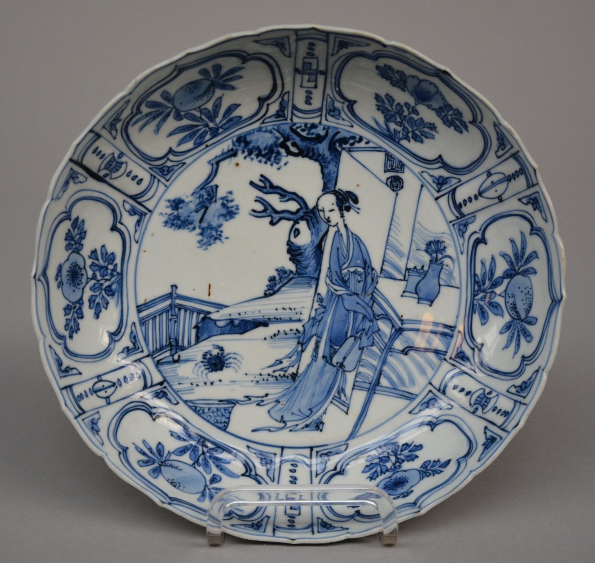 A Chinese blue and white plate with fluted rim and relief decoration, painted with a lady in a