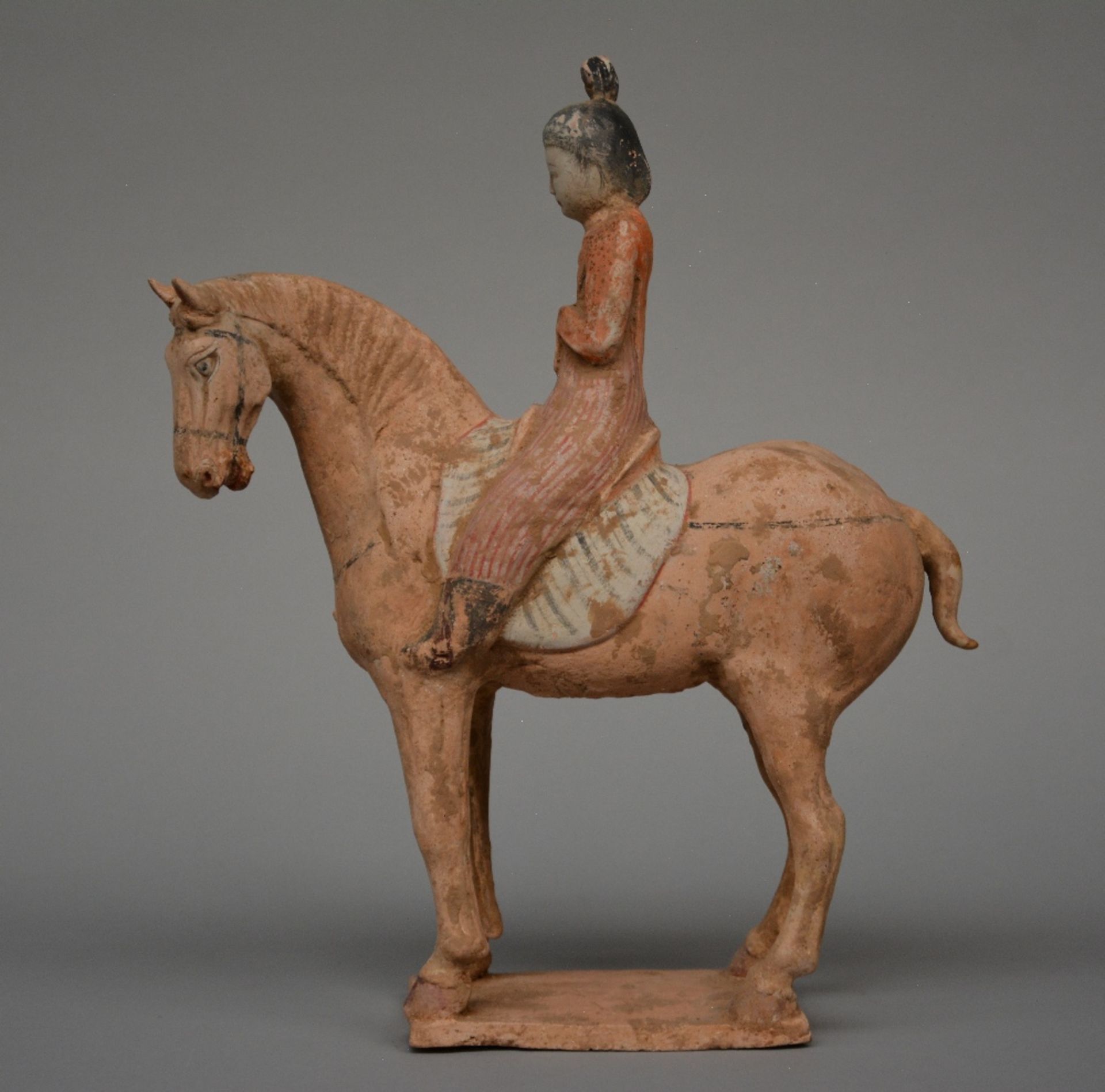 A Chinese earthenware figure of a horse rider, with traces of polychrome, Tang dynasty (618-906),