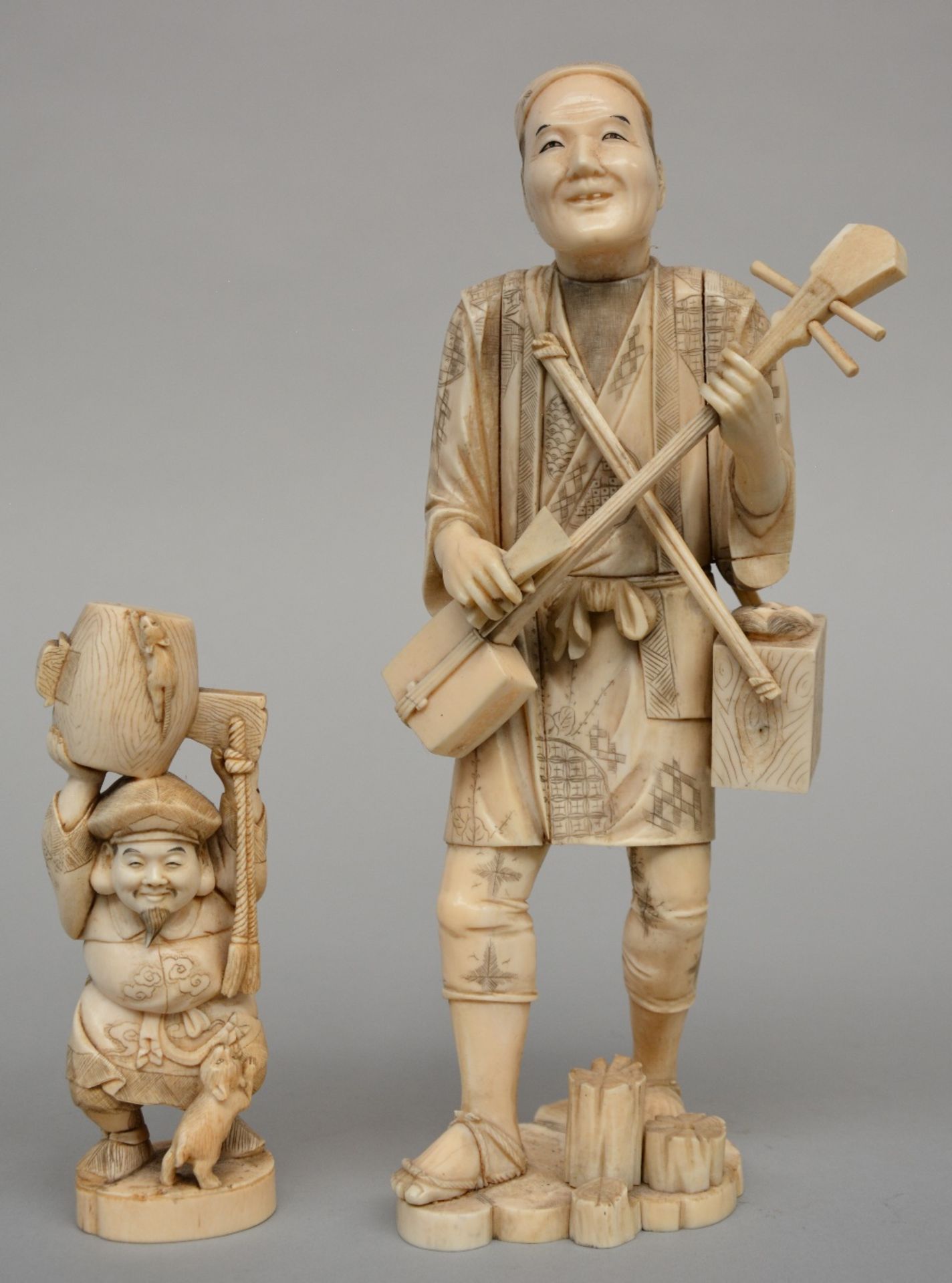 A Japanese ivory okimino of a street musician scrimshaw decorated, Meiji period, H 29,3 cm, Weight