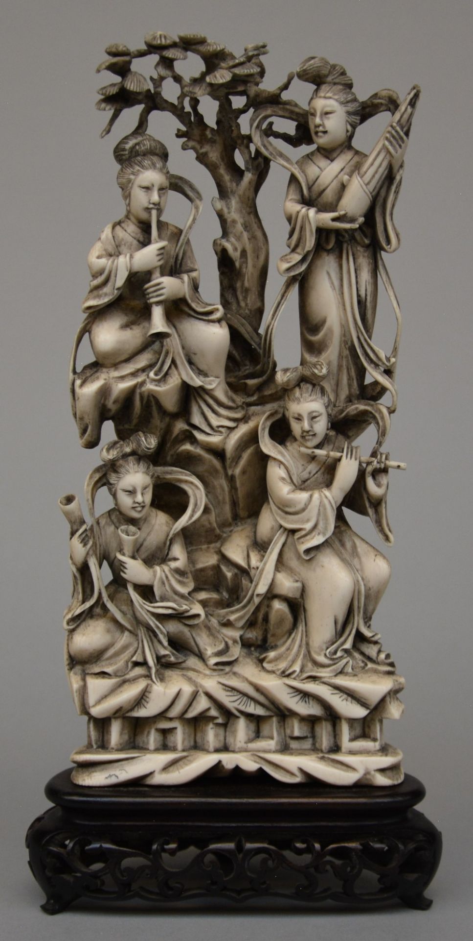 A Chinese ivory sculpture carved with ladies playing music in a landscape, on a fixed wooden base, H