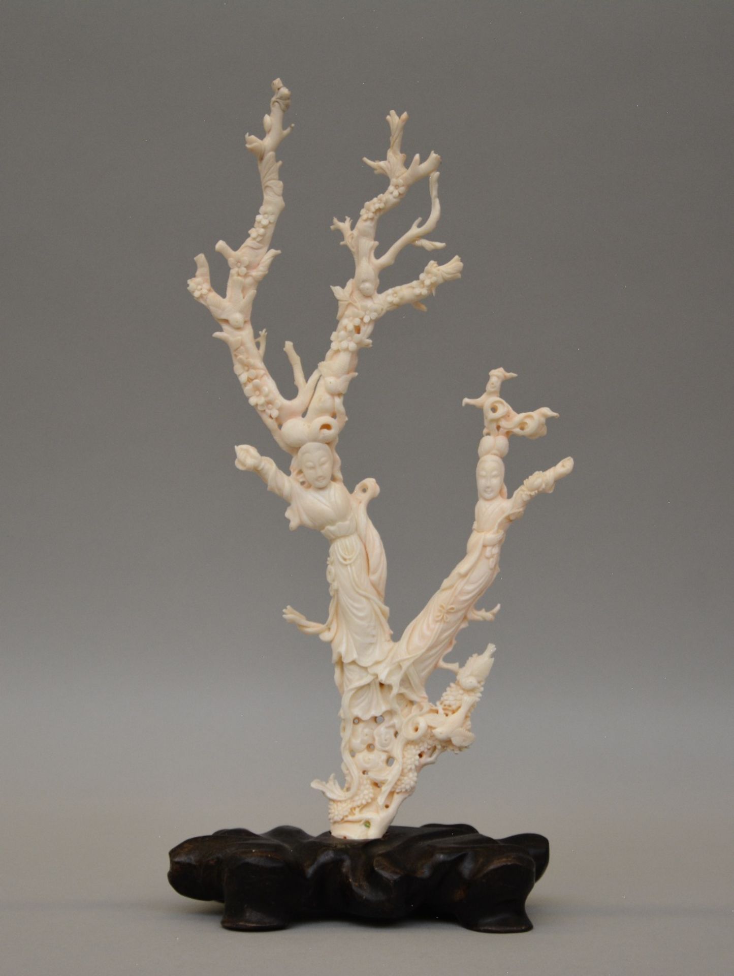 A Chinese white coral sculpture carved with figures, birds and flowers, on a wooden base, H 45