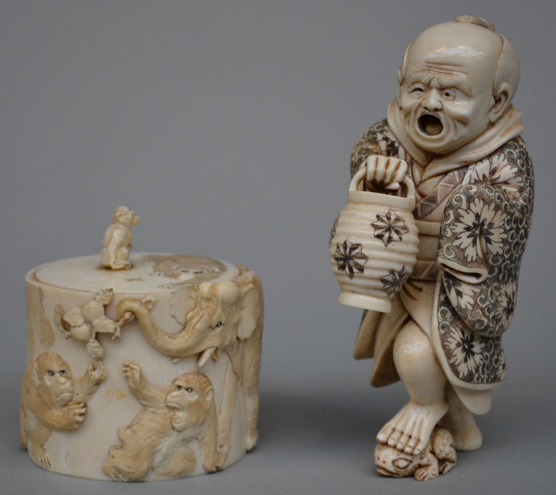 A Japanese ivory okimono of a man holding a lantern and stepping on a toad, scrimshaw decorated,