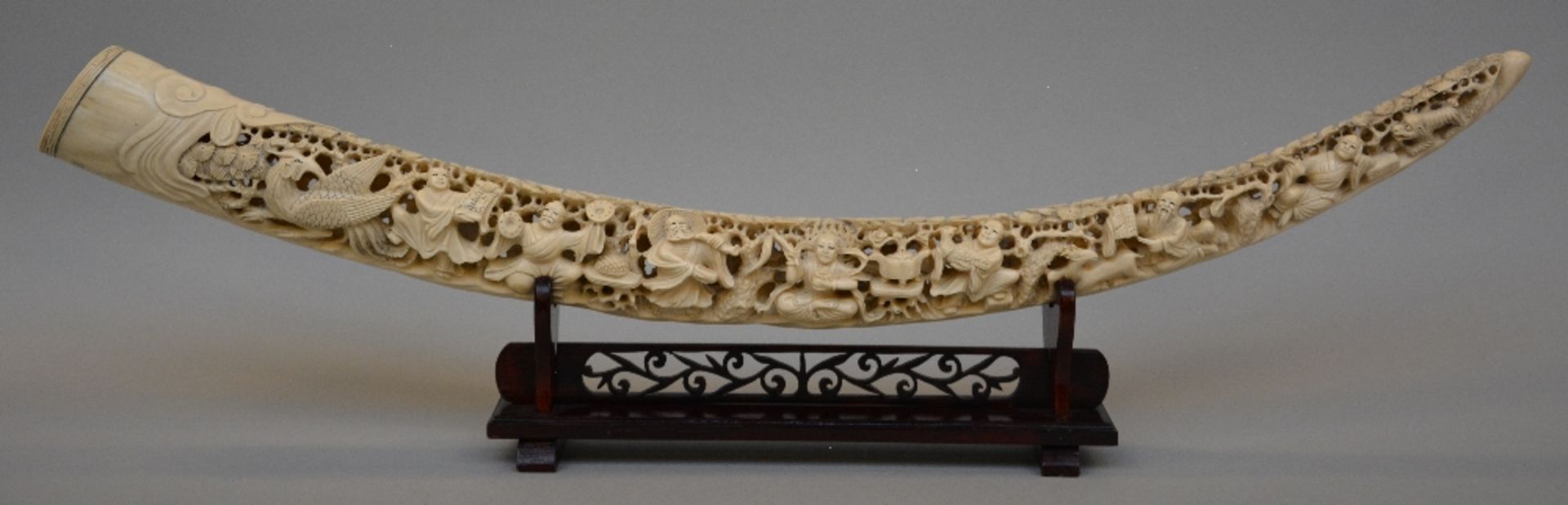 An ivory tusk carved with animated scenes, on a matching wooden base, first half of 20thC, L 86,5