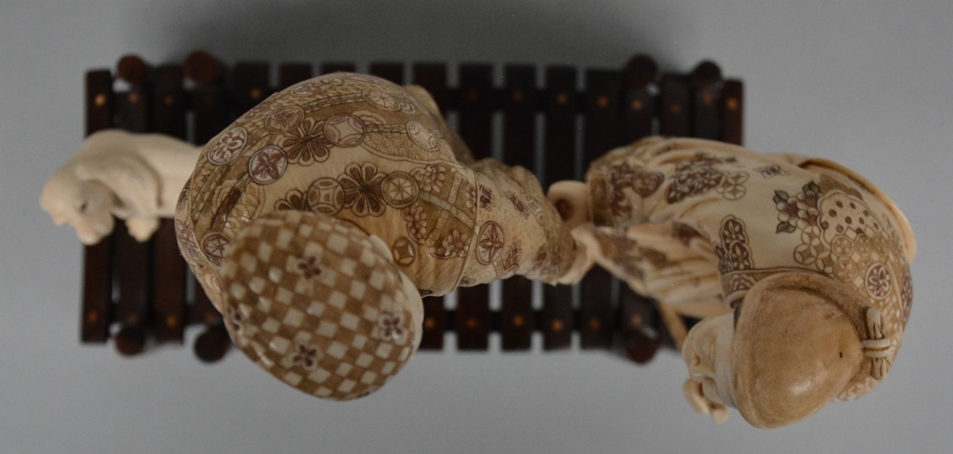 A charming Japanese ivory okimono depicting two figures and a dog on a bridge, red and black - Image 5 of 5