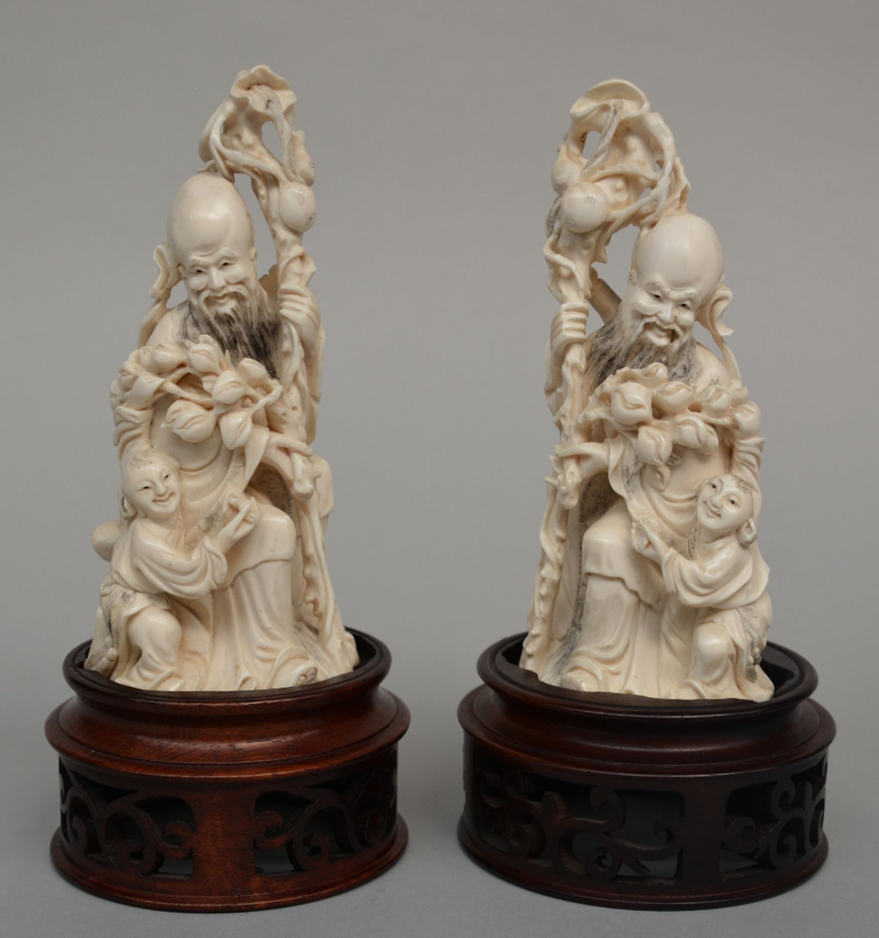 A pair of ivory figures of Shou Xing on a wooden base, scrimshaw deocrated, first quarter of