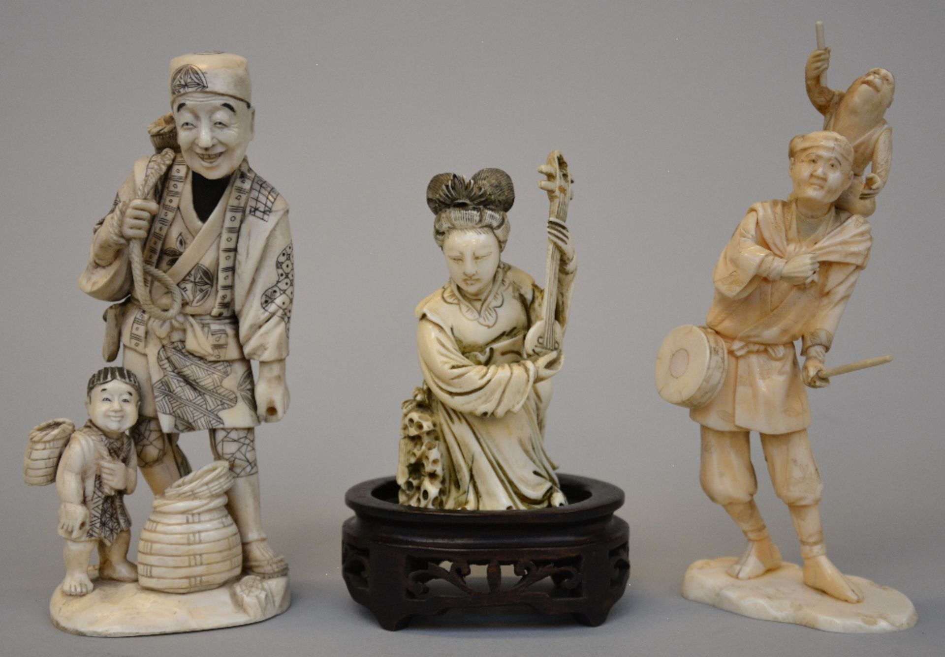 Two Japanese ivory okimono figures of a peddler with son and a street musician with monkey, both
