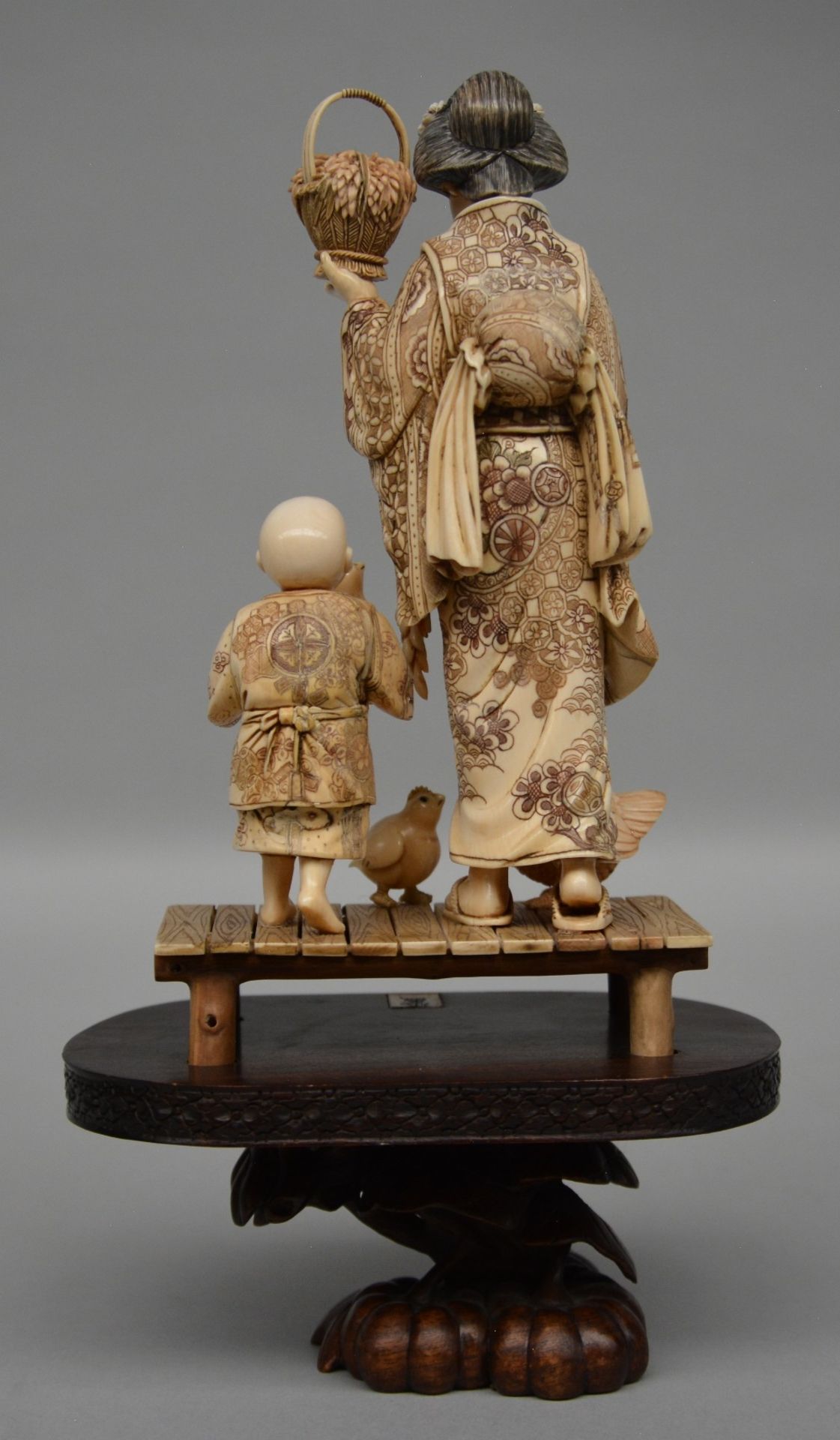 A charming Japanese ivory okimono decorated with red and black scrimshaw, on a wooden base, ca. - Image 3 of 6