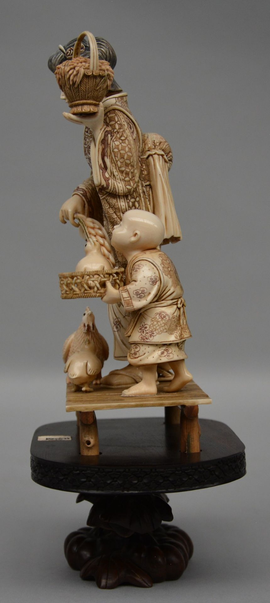 A charming Japanese ivory okimono decorated with red and black scrimshaw, on a wooden base, ca. - Image 2 of 6