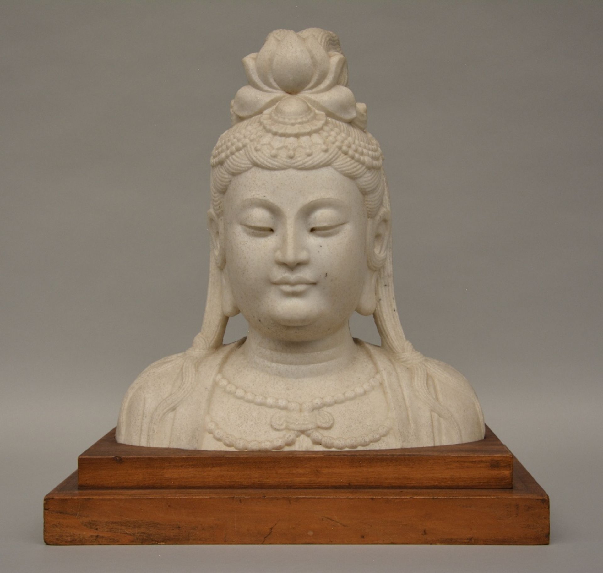 A stone Buddha head, on a wooden base, H 40 cm