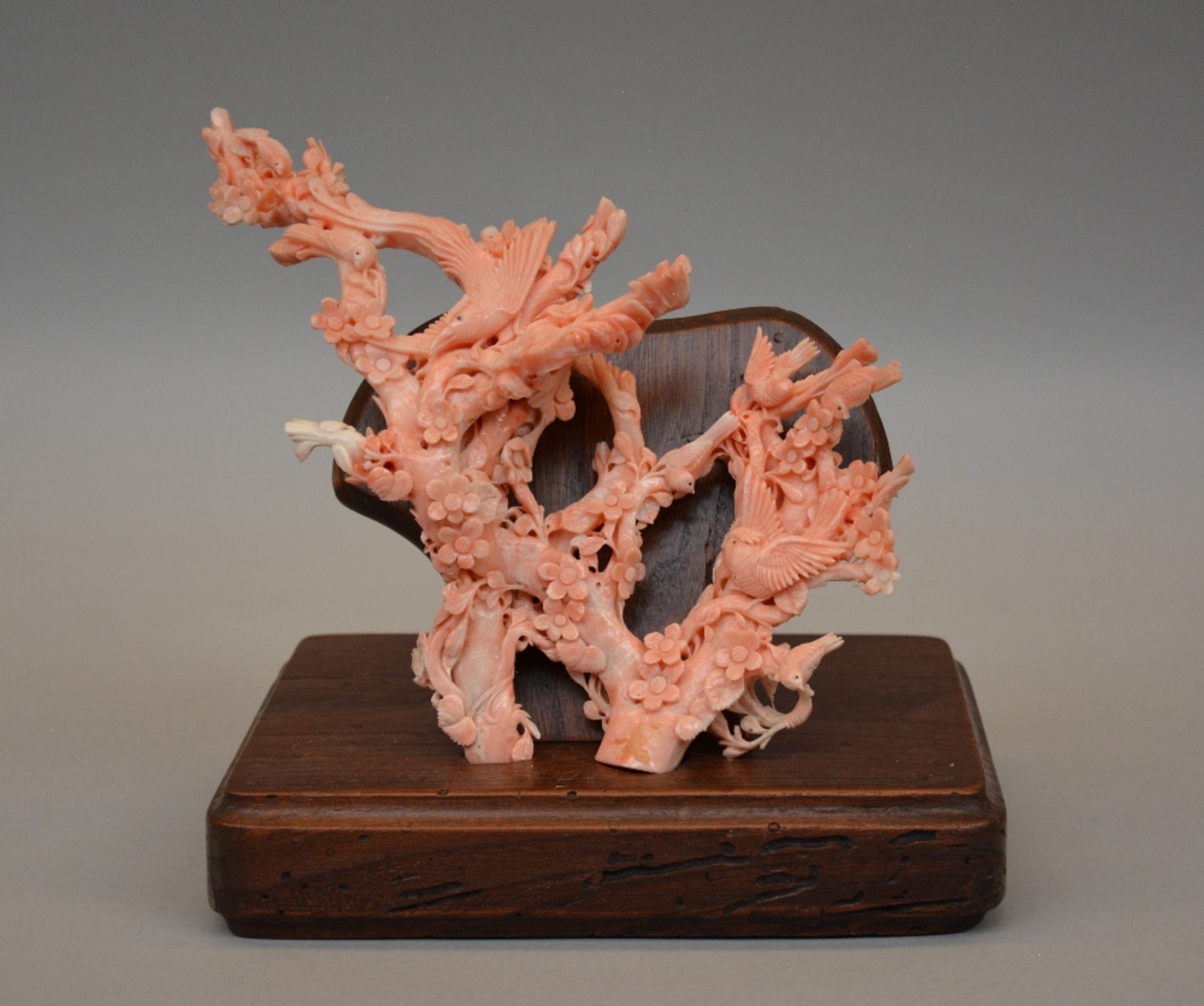 A Chinese red coral sculpture depicting birds and flowers, on a wooden base, H 19,5 - Weight about