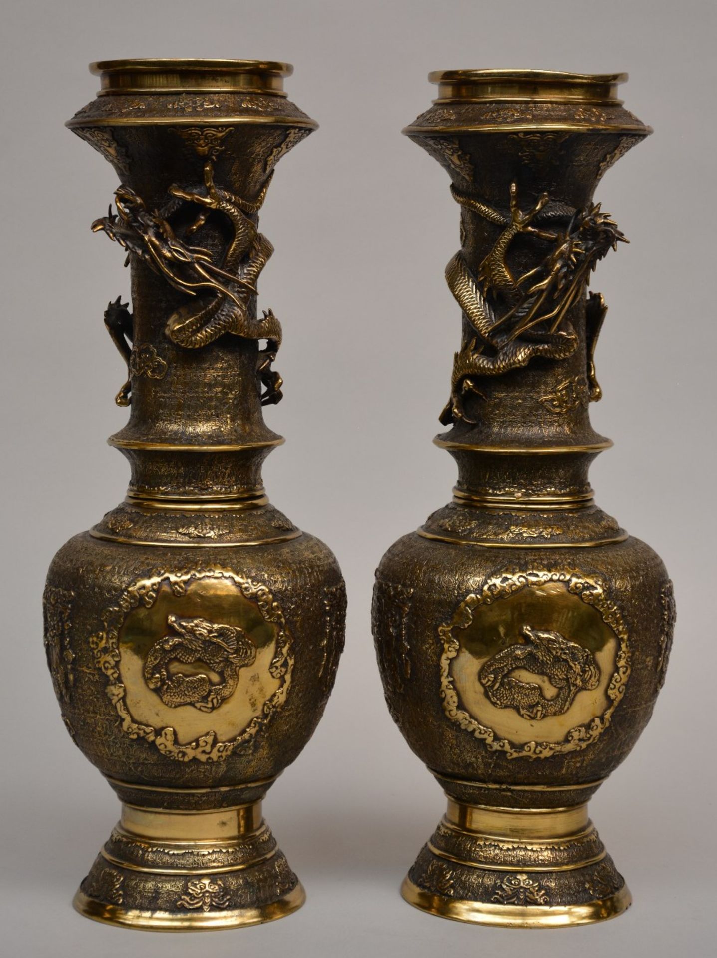 A pair of Oriental bronze vases with relief decoration of dragons, 19thC, H 49 cm