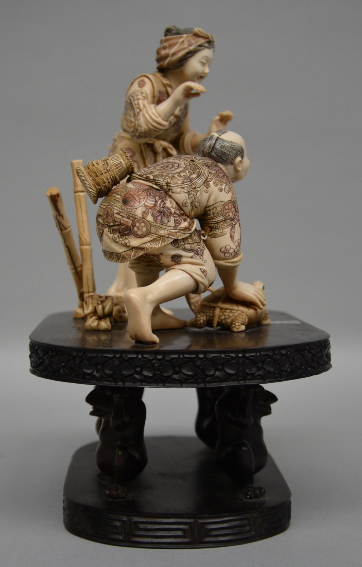 A charming Japanese ivory okimono of two figures playing with a tortoise, red and black scrimshaw - Image 4 of 6