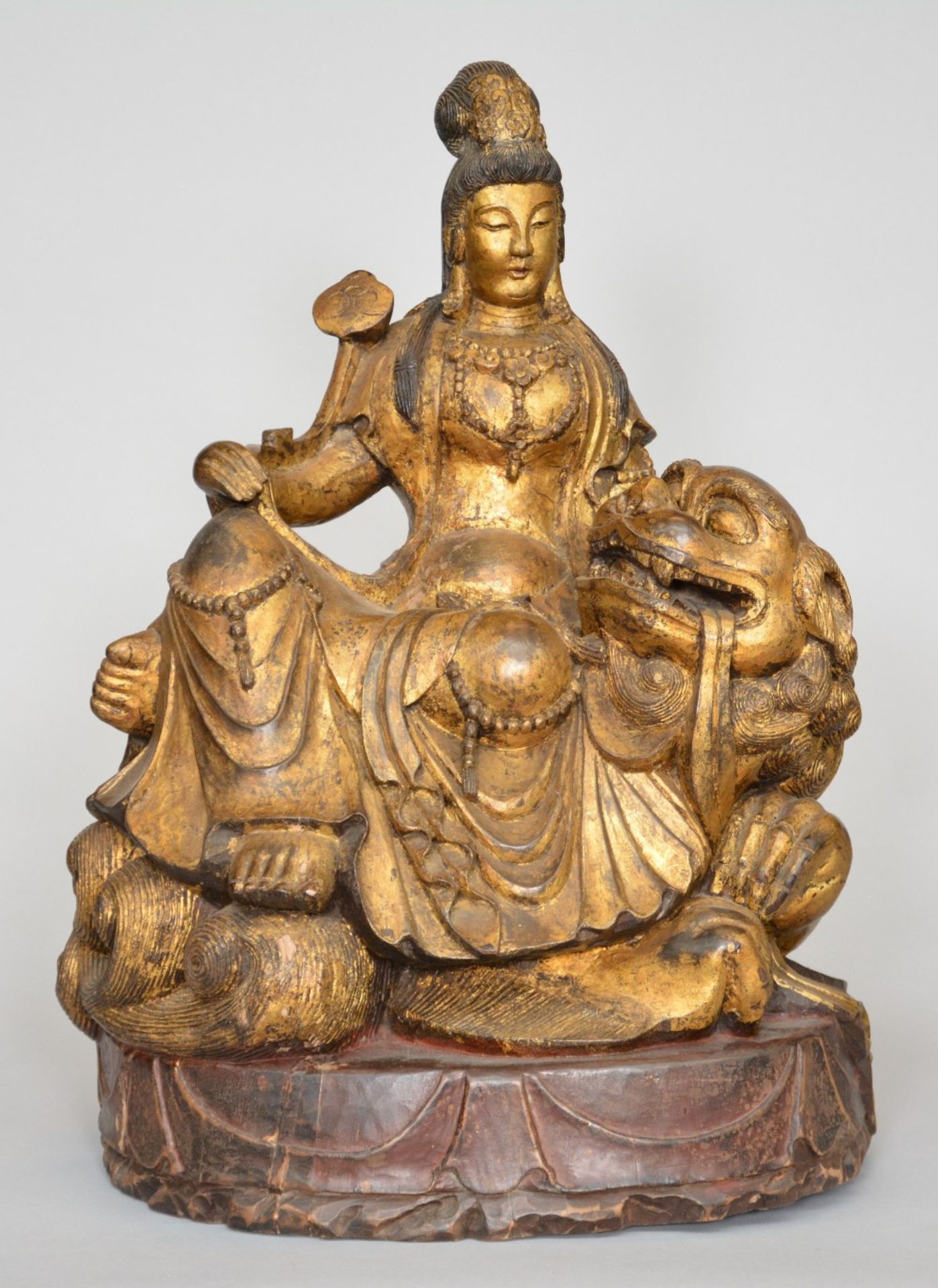 A Chinese polychromed and gilt wooden sculpture figuring a Guanyin sitting on a Fu lion, ca. 1900, H