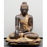 A rare Oriental gilt and polychrome decorated wooden Buddha, inlaid with rock crystal and other