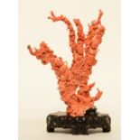 A Chinese red coral sculpture carved with figures, children, flowers and fish, on a wooden base, H