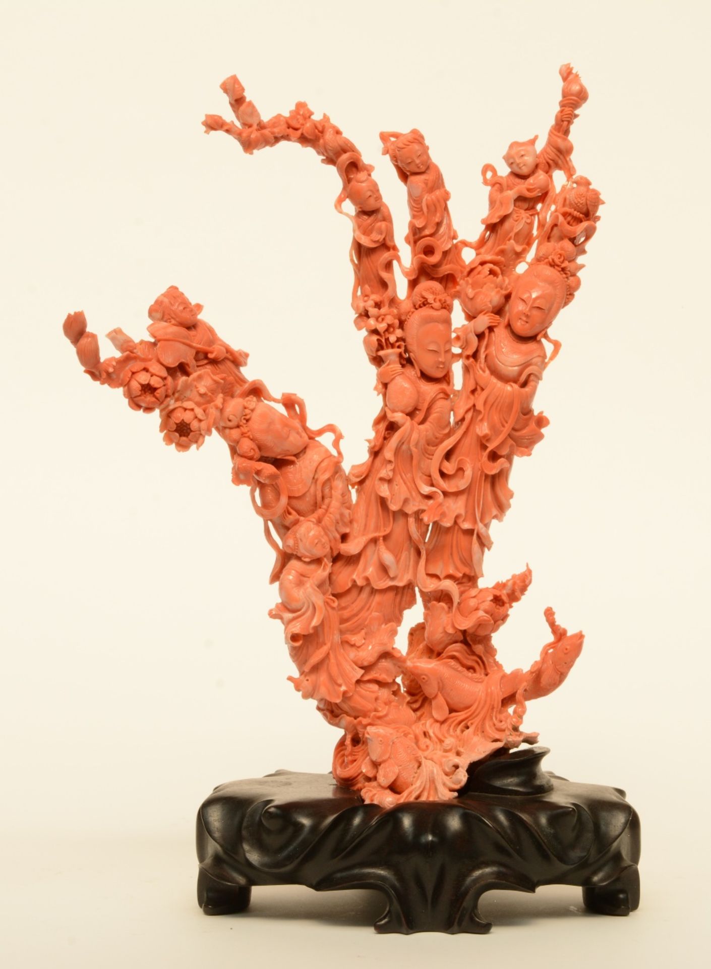 A Chinese red coral sculpture carved with figures, children, flowers and fish, on a wooden base, H