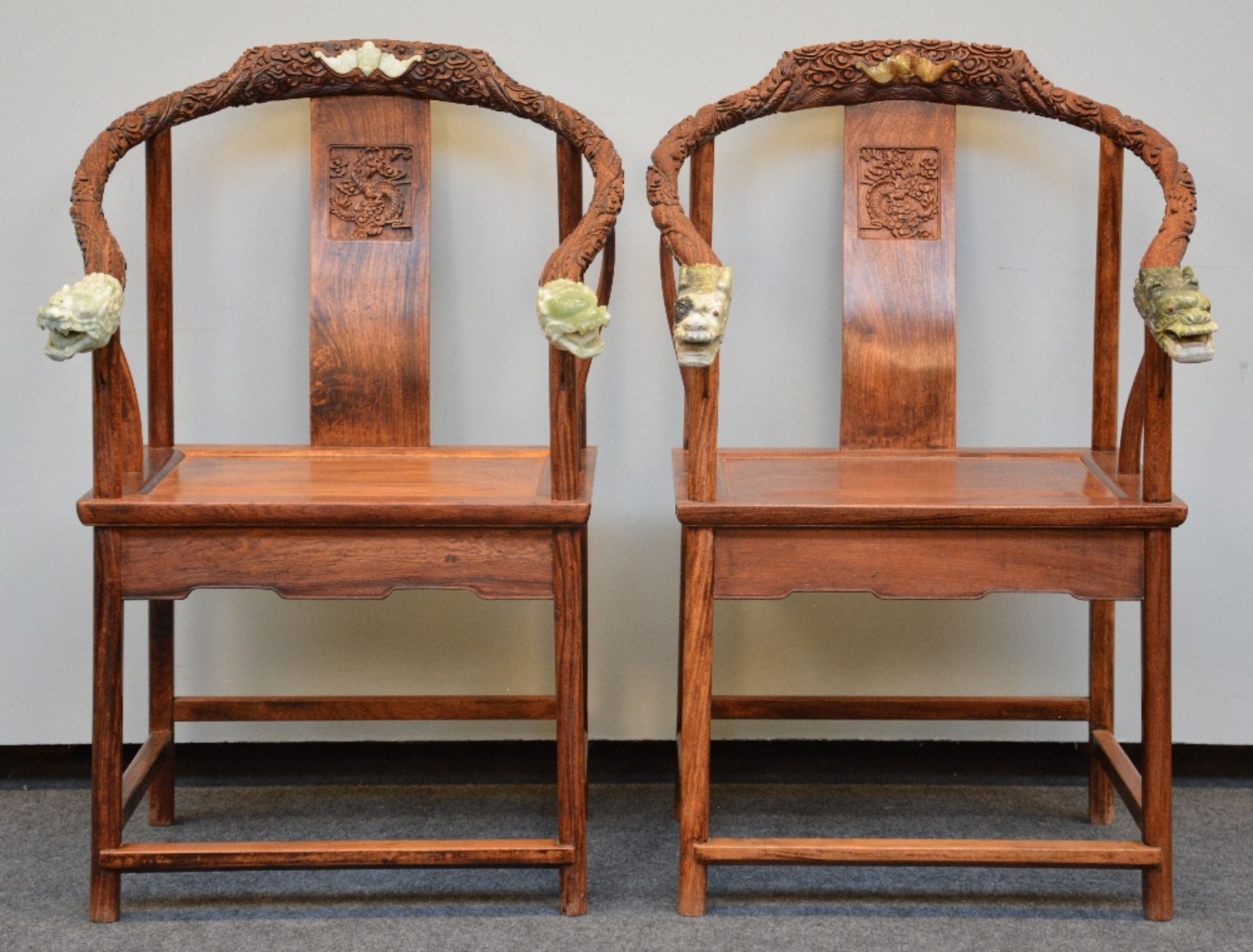 A pair of Chinese armchairs in exotic wood, the horseshoe-shaped back richly carved and crowned with