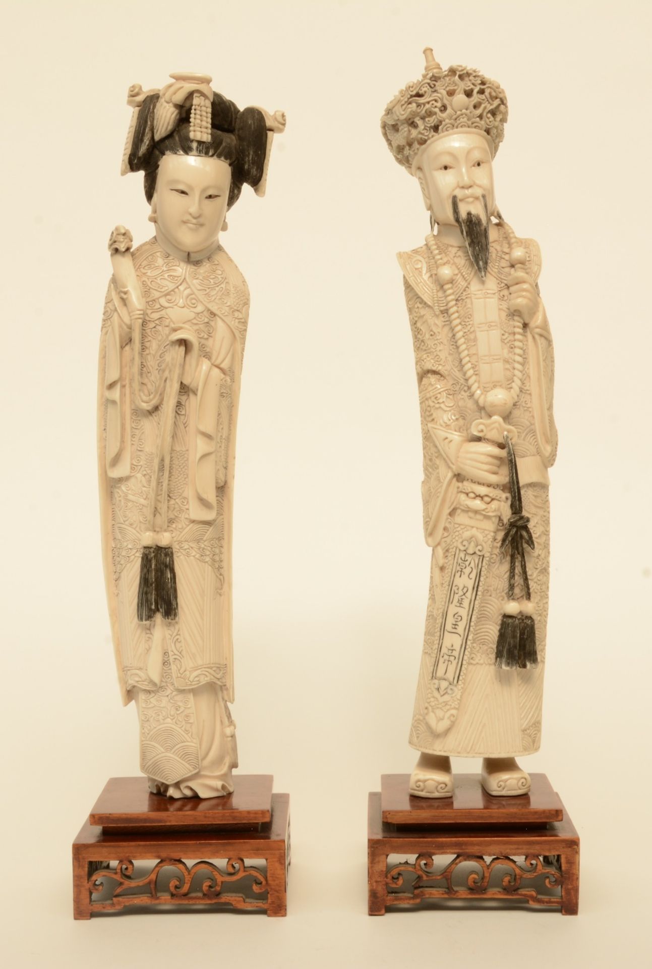 A pair of Chinese ivory figures of the imperial couple, on a fixed wooden base, scrimshaw decorated,