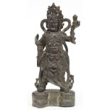 A Chinese bronze temple guard on matching base, H 33 cm (left arm restored, a part of the ribbon