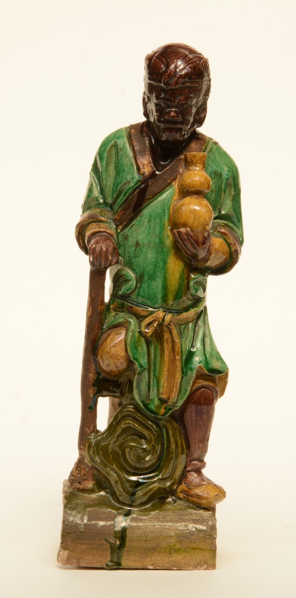 An earthenware roof-figure depicting one of the Immortals, brown, yellow and green enameled,