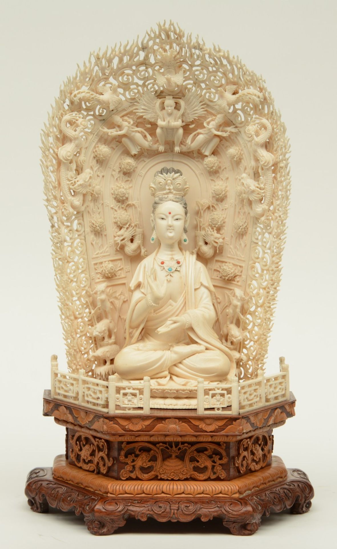 A Chinese ivory Guanyin, scrimshaw decorated, inlaid with various semi-precious stones, on a