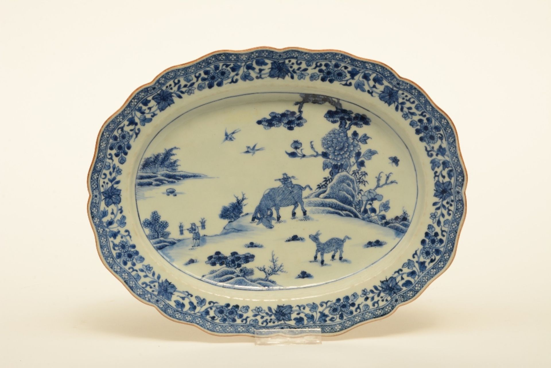 A Chinese oval dish with profiled rim, blue and white decorated with a landscape and floral