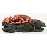A Chinese monochrome red ivory sculpture depicting a mythological animal, on a wooden base, 19thC, H