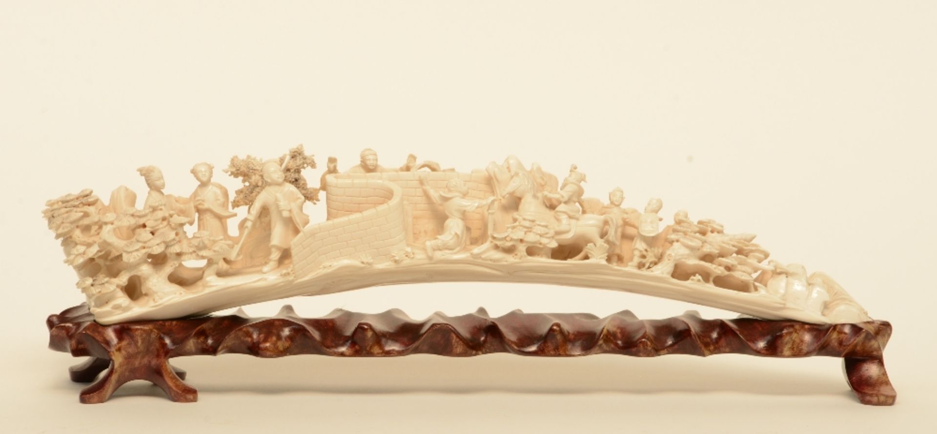 An ivory tusk carved with animated scenes, on a matching wooden base, first half of 20thC, L 45,5 cm