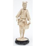 A Japanese ivory okimono depicting a fish seller, slightly scrimshaw decorated, on a wooden base,