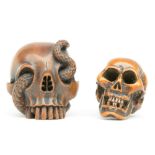 Two Japanese boxwood katabori netsuke in the form of a human skull (one with a snake on top), Edo-