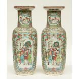 A pair of Chinese 19thC famille rose rouleau vases decorated with animated scenes and birds on