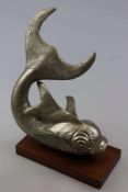 Metall-Skulptur, silberfarben, Darstellung eines Fabelfisches mit erhobener Schwanzflosse, auf einem
