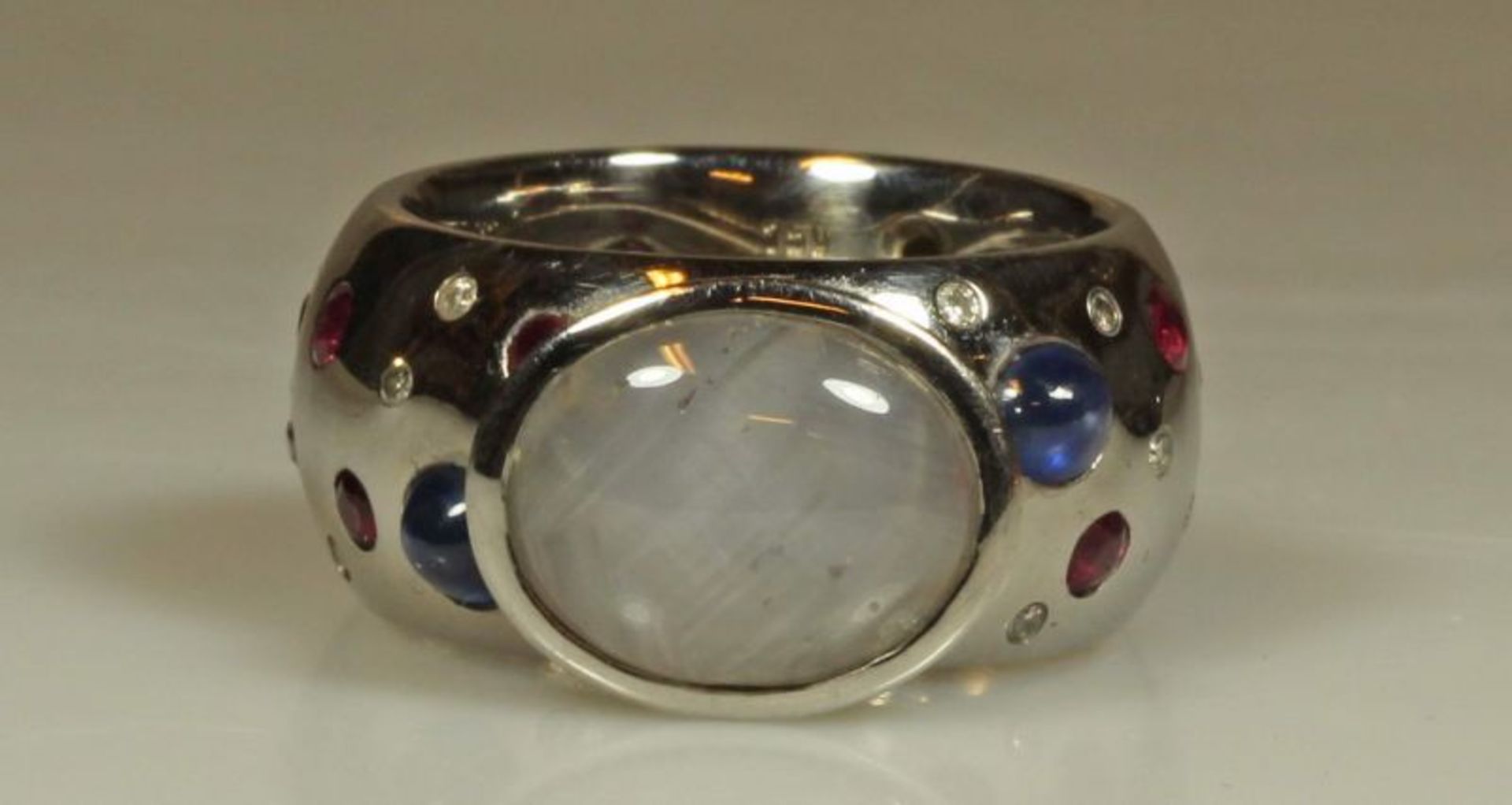 Ring, GG 750, großer Sternsaphir-Cabochon, Schiene besetzt mit 2 Saphir-Cabochons, je 16 Rubine