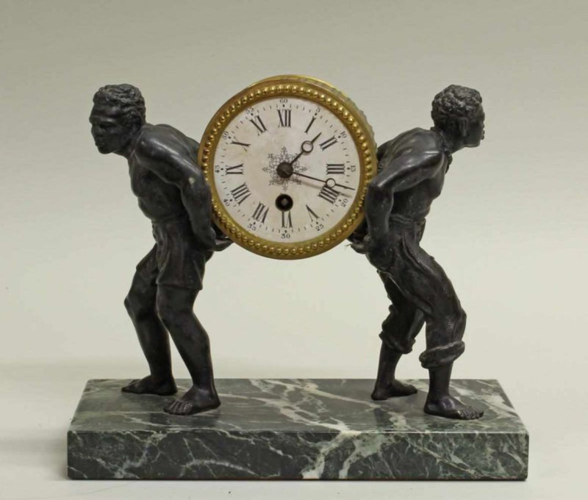 Tischuhr, um 1900, zwei Afrikaner aus Bronze tragen das runde Uhrengehäuse, weißes Emailzifferblatt,
