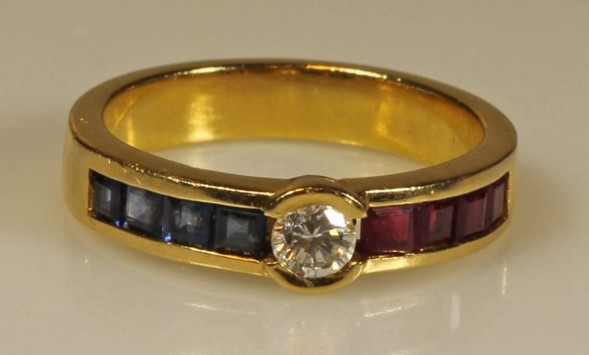Ring, GG 750, 1 Brillant ca. 0.10 ct., je 4 quadratisch facettierte Rubine und Saphire, 6 g, RM 17.5