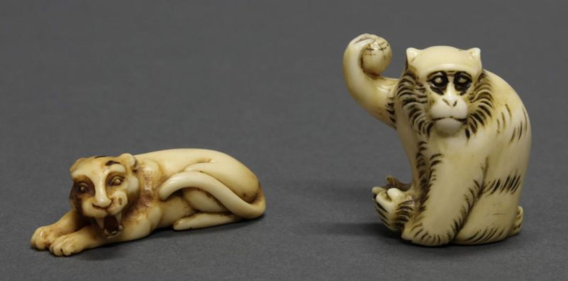 2 Netsuke, "Liegender Tiger", "Affe", Japan, 19./20. Jh., Hirschhorn bzw. Elfenbein, geschnitzt,