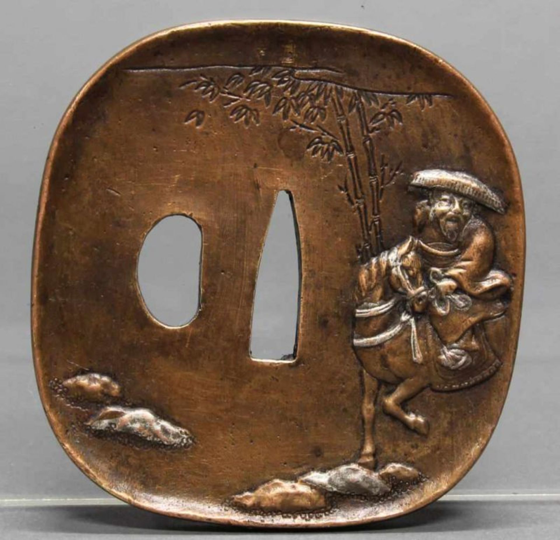 Tsuba, Japan, 19./20. Jh., Kupfer, abgerundete Ecken, im Relief ein Reiter unter Bambus,