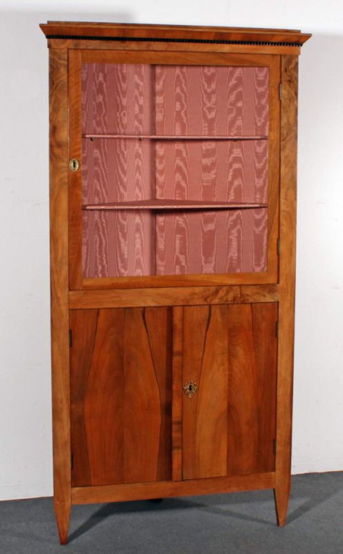 Eckvitrine, Biedermeier-Stil, 20. Jh., Nuss-/Nussmaserholz, Oberteil eine Glastür, Unterteil zwei