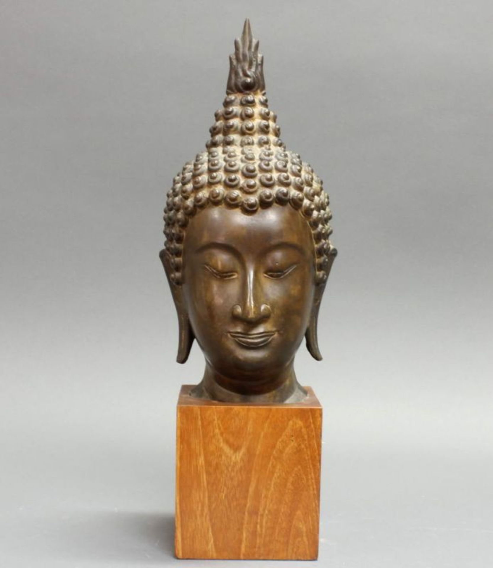 Buddhakopf, Thailand, 20. Jh., Bronze, auf Holzsockel, 31 cm bzw. 42 cm hoch (mit Sockel), kleine