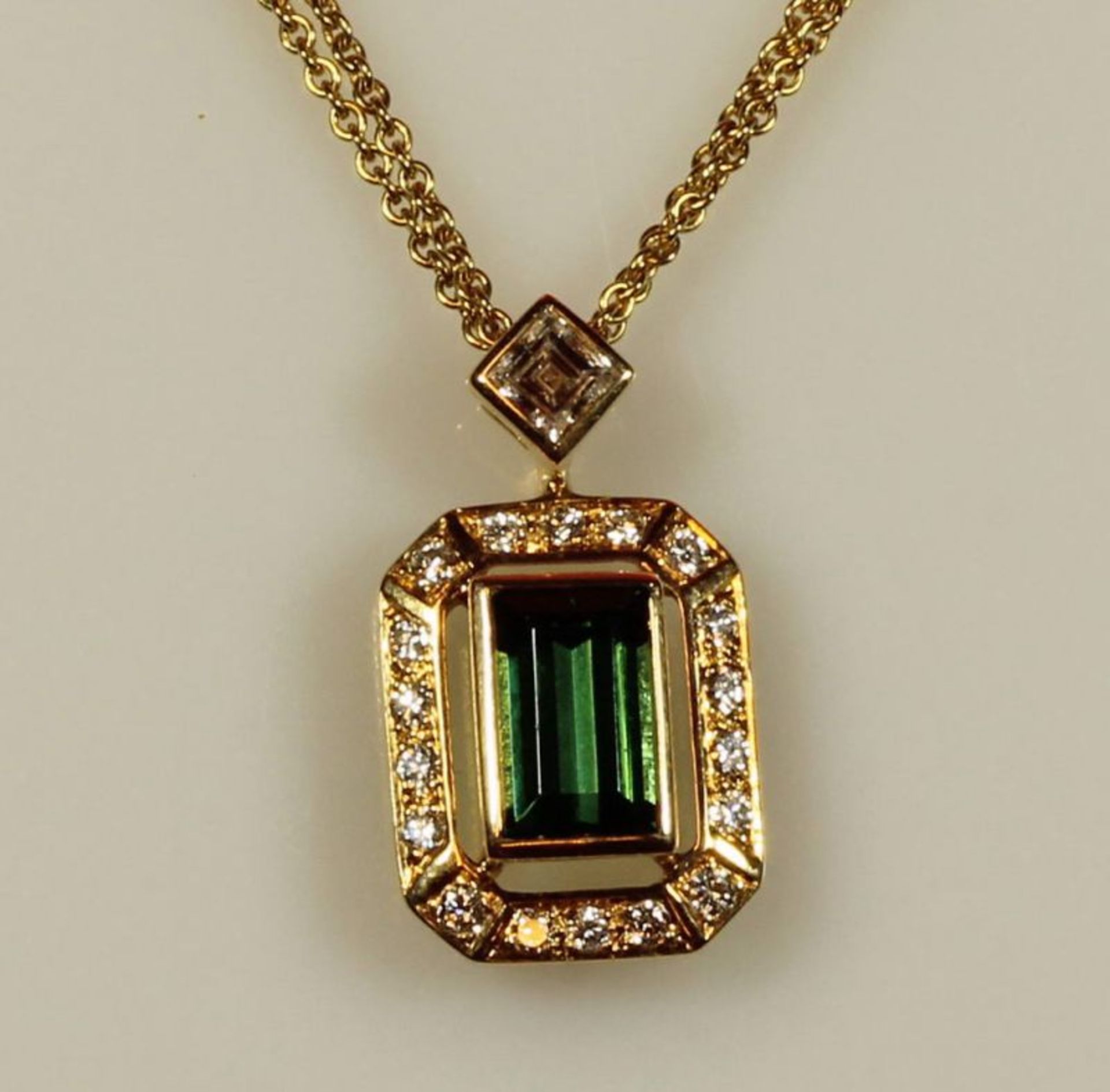 Collieranhänger, GG 750, 1 grüner Turmalin ca. 1.30 ct., im Baguettschliff, 1 Diamantcarrée, ca. 0.