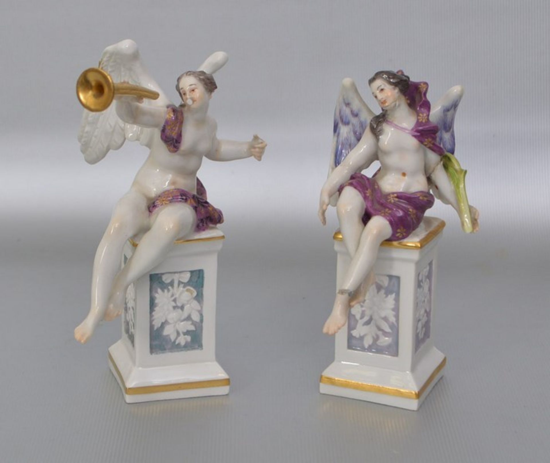 Zwei sitzende Engel auf verziertem Postament sitzend, mit Trompete bzw. mit Zweig, bunt bemalt,