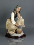 Porzellanfigur (Lladro, 20.Jh.)"Sitzendes Mädchen"; auf geschwungenem Sockel; farbig bemalt;