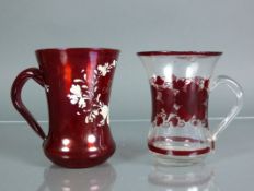 2 Henkelbecher (19.Jh.)jeweils mit tailliertem Korpus; farbloses Glas mit roter Lasur;