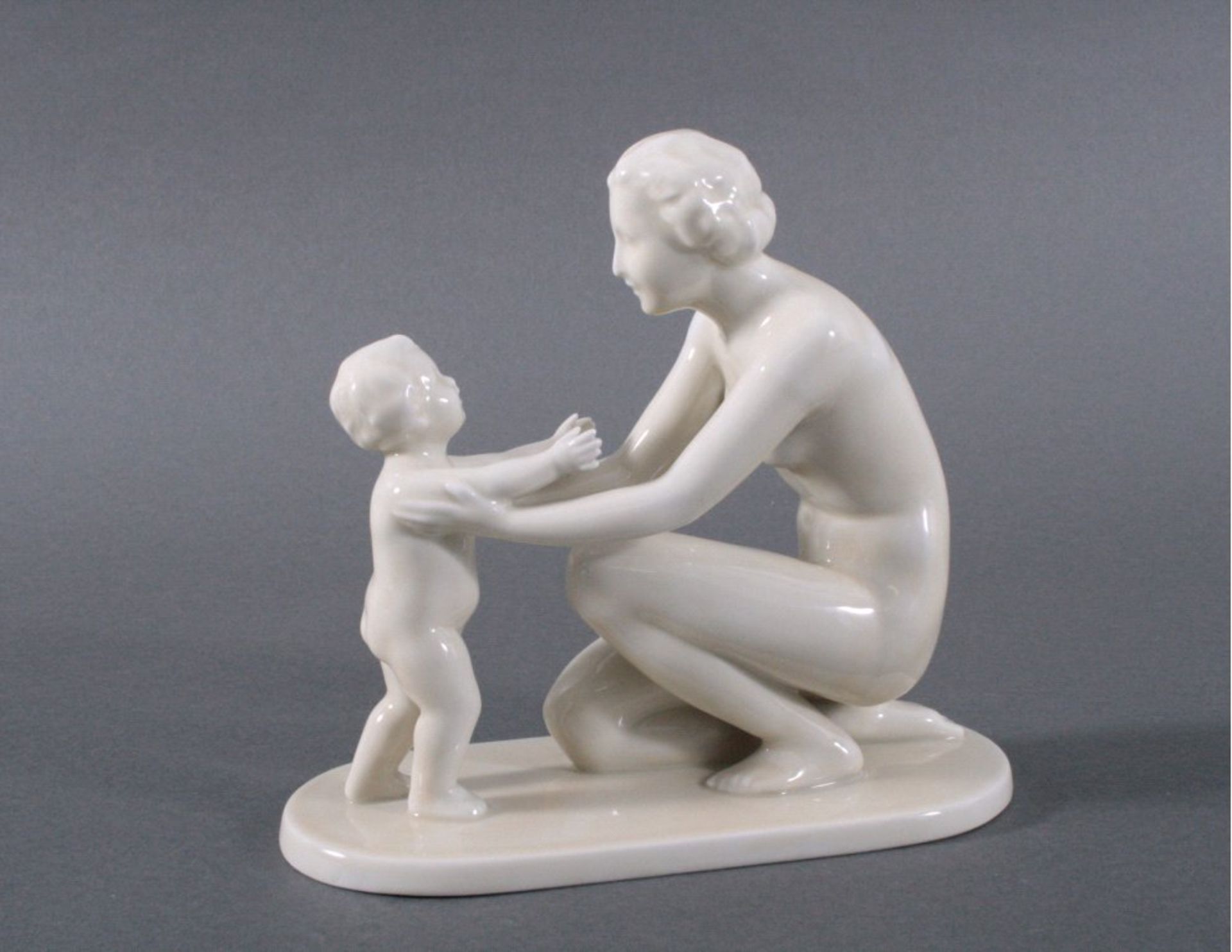Porzellan-Skulptur "Mutter mit Kind"Tettau nach 1935, weiß glasiert, auf ovaler Plinthe kniendejunge