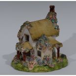 A Staffordshire cottage pastel burner, applied with shredded clay moss and flowerheads, in tones