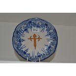 A French Faience tin glazed shaped circular dish, decorated with a cross,