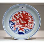 A Chinese dish, decorated in underglaze blue, boldly painted with red dragons,