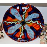 A Poole Delphis charger, decorated in tones of red blue and green,