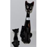 A 1970'S stylised cat , with elongated neck , silvered eyes and bow, picked out in red ,